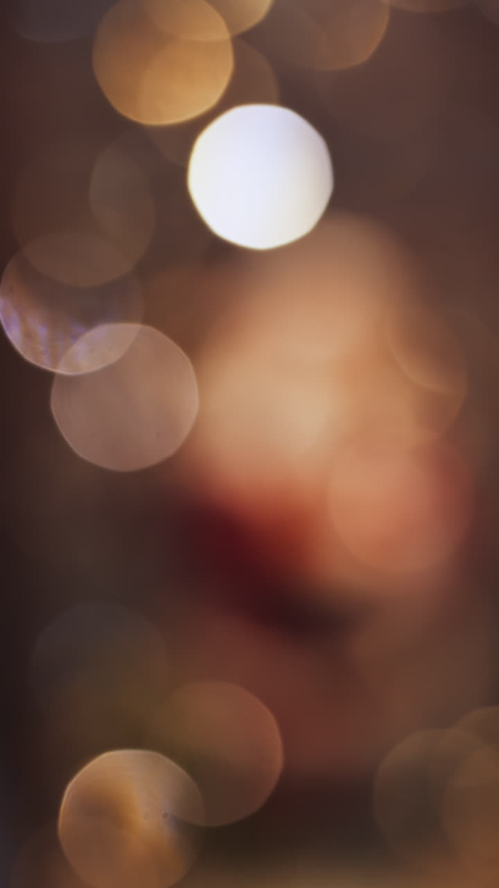 Close up of a blurred Santa Clause figurine in a snow globe with sparkles floating in it. Vertical