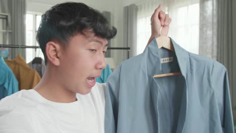 close up of asian man online seller recommending a shirt and recording video while selling clothes at home