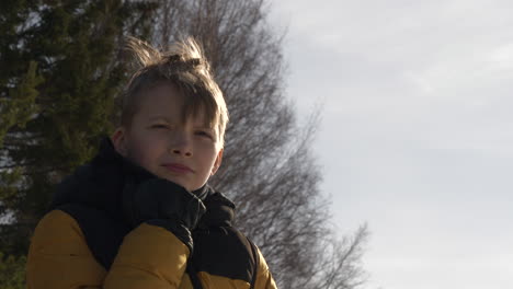 joven con abrigo de invierno al aire libre mirando a lo lejos como sopla el viento