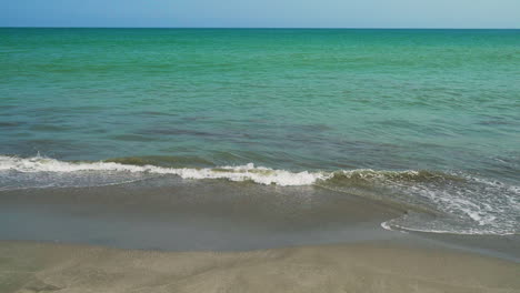 Close-up-shot-of-the-small-tide-of-the-blue-sea-reaching-the-shore-of-the-Zorritos-beach,-Tumbes,-Peru