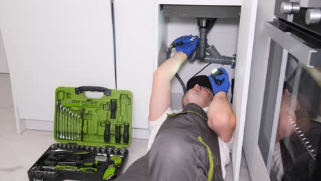 top view of an appliance technician working under a kitchen sink installing a sink