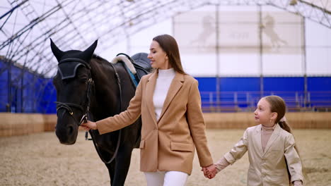 mother and daughter with horse in indoor arena