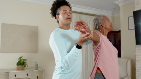 caregiver assisting senior woman with arm exercises at home, promoting wellness