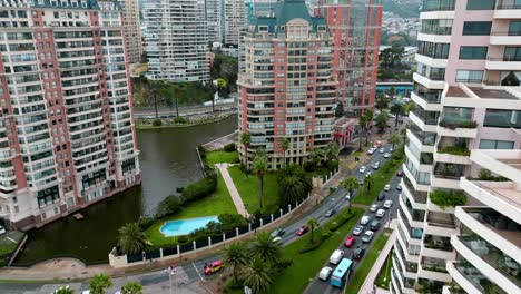 Plataforma-Rodante-Aérea-De-Lujosos-Edificios-Complejos-Con-Estanque-Artificial-Y-Vegetación-Cerca-De-Una-Concurrida-Avenida-Y-Rotonda-En-Viña-Del-Mar,-Chile