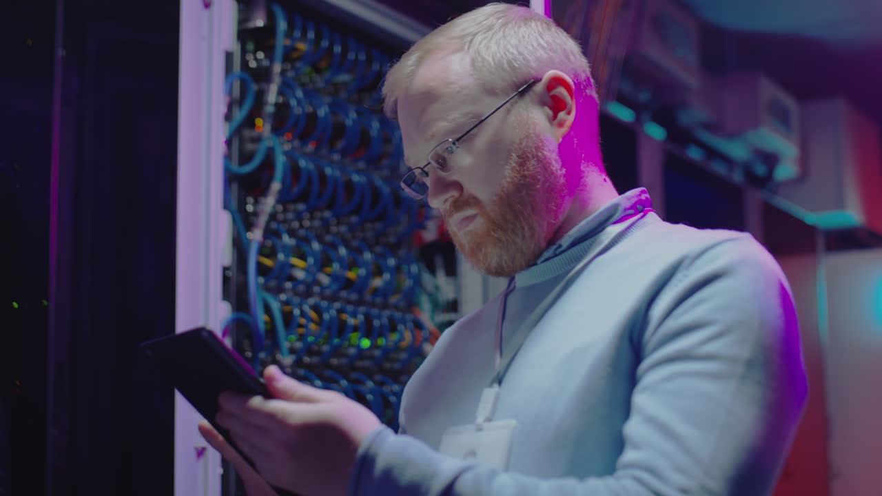 IT Professional Working in a Server Room with a Tablet