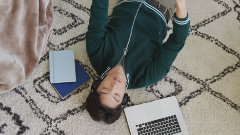 overhead view of asian boy playing with basketball lying on the floor at home