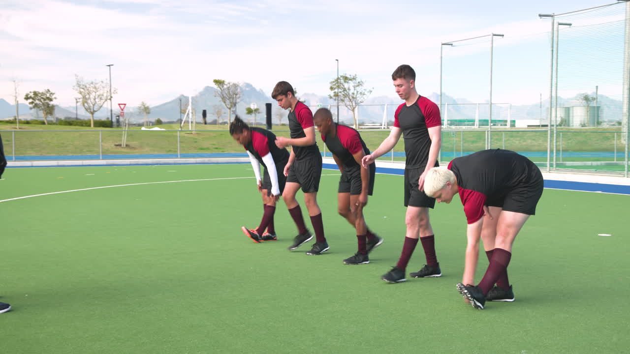 Male hockey players stretching and warming up on field before practice