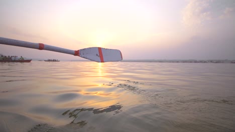 oar entering the water at sunset