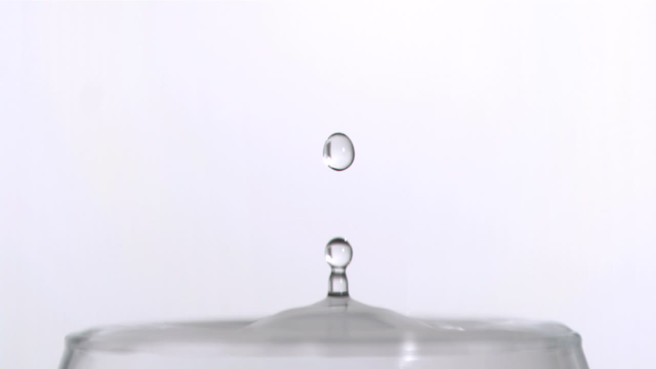 una gota cayendo en cámara súper lenta en un vaso