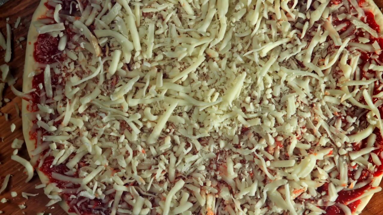 Cospargere mozzarella grattugiata su pizza cruda