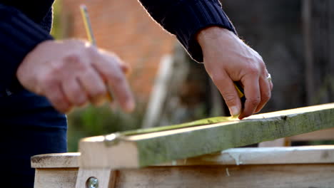 mature man measuring and sawing wood in slow motion