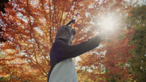 Cheerful-child-in-deer-costume-dancing-near-autumn-tree