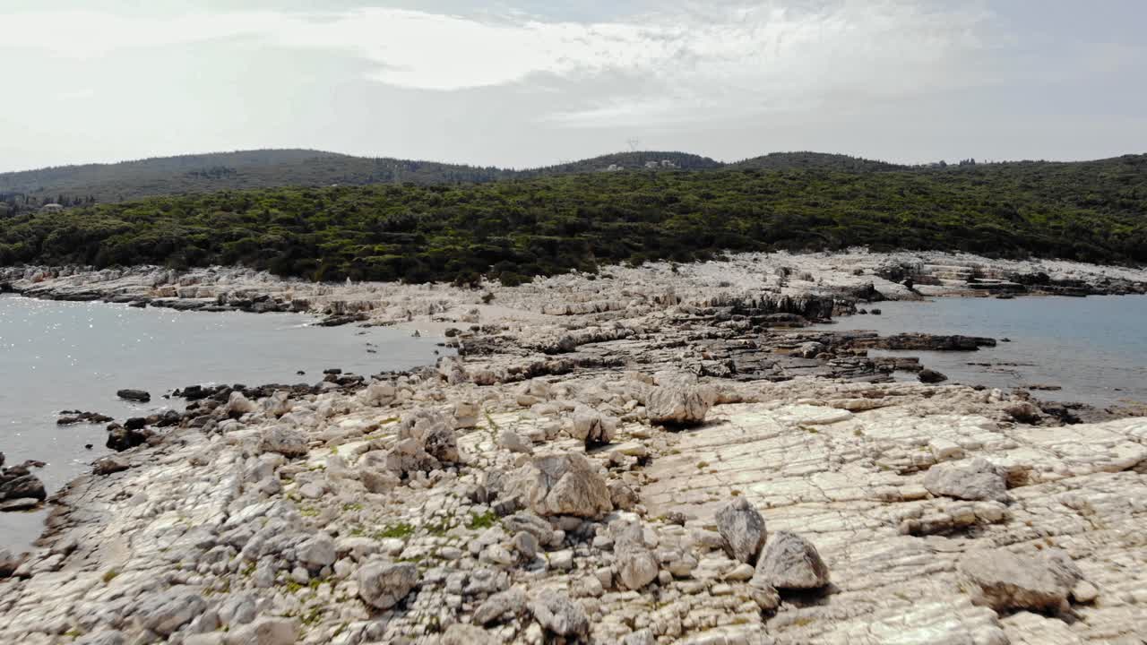 barra de piedra blanca en la playa de paralia emplisi - paisaje verde de la isla de kefalonia en el fondo - toma aérea