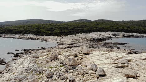 Barra-De-Piedra-Blanca-En-La-Playa-De-Paralia-Emplisi---Paisaje-Verde-De-La-Isla-De-Kefalonia-En-El-Fondo---Toma-Aérea