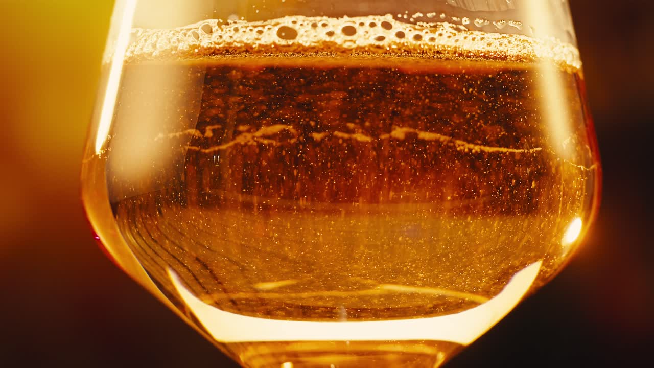 Orange or white wine bottle and glass against a sunset in a peaceful vineyard, pouring of ecological natural wine.