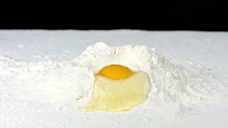 footage of an egg being in some flour, against a black background