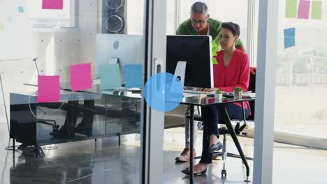 Animation-of-network-of-digital-icons-over-diverse-man-and-woman-discussing-over-computer-at-office