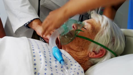 doctors placing an oxygen mask and adjusting a iv drip to patient in ward