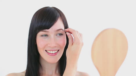 una mujer sonriente arrancándose la ceja.