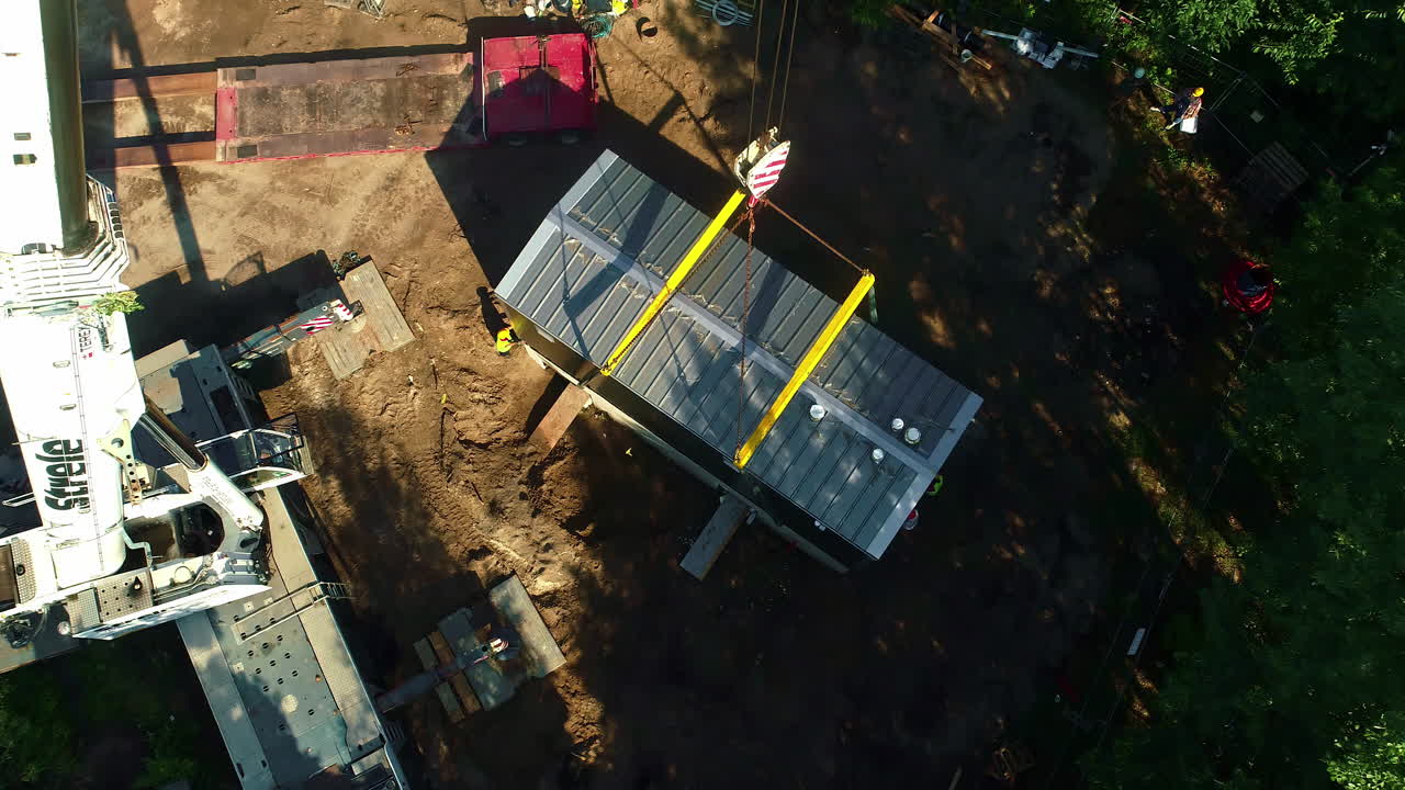 sitio de construcción que utiliza una grúa para mover contenedores metálicos casa modular por los trabajadores