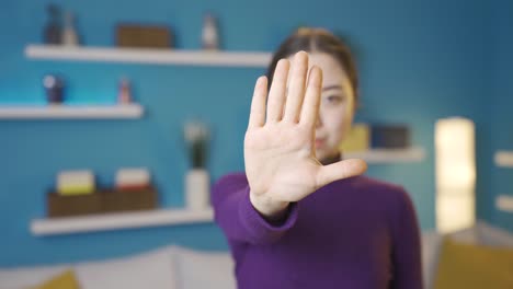 asian woman gesturing stop sign at camera approaching her.