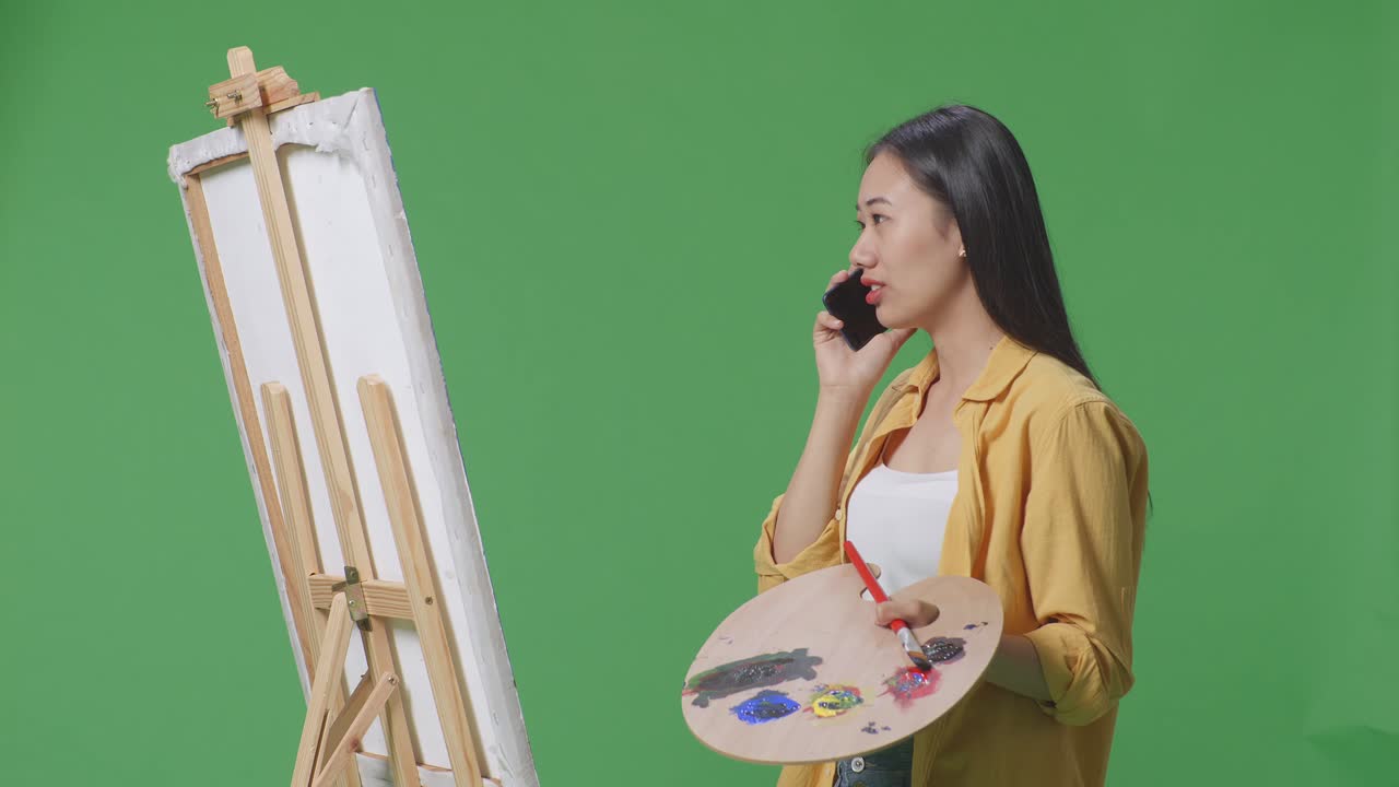 그림을 그리는 동안 전화로 이야기하는 여성 예술가