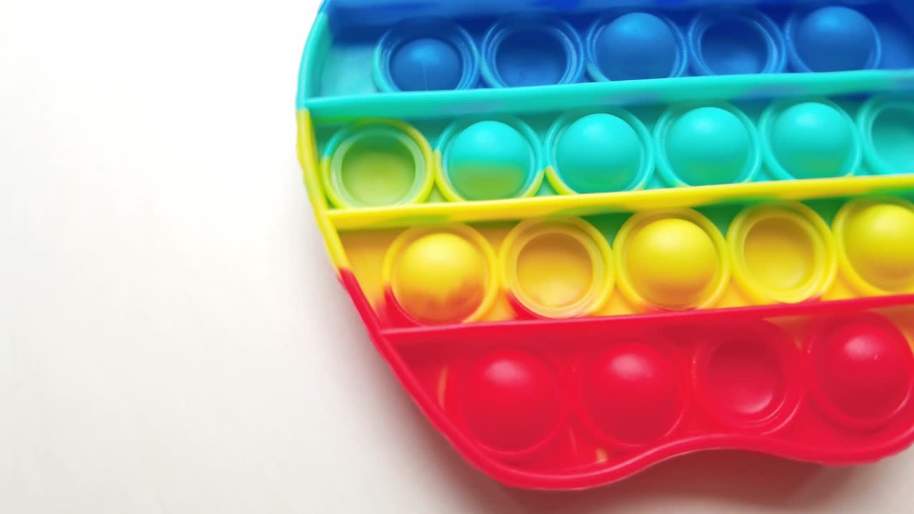nuevo juguete para bebés. pop it juego de dedos. color gracioso. colorido juego girar en la mesa blanca. forma de manzana arco iris