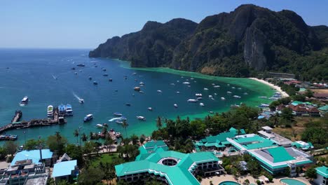 Turquoise-water-laps-gently-at-the-shore-of-a-tropical-island,-with-boats-dotting-the-seascape-and-lush-green-hills