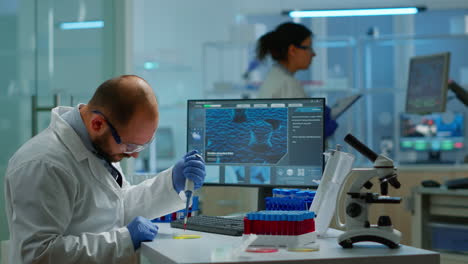 hombre científico que utiliza micropipeta para llenar tubos de ensayo en un laboratorio modernamente equipado