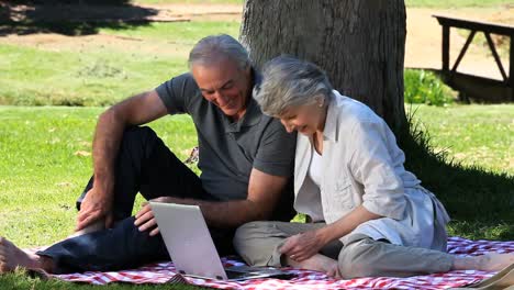 Old-man-and-woman-using-a-laptop-sitting-on-a-tablecloth