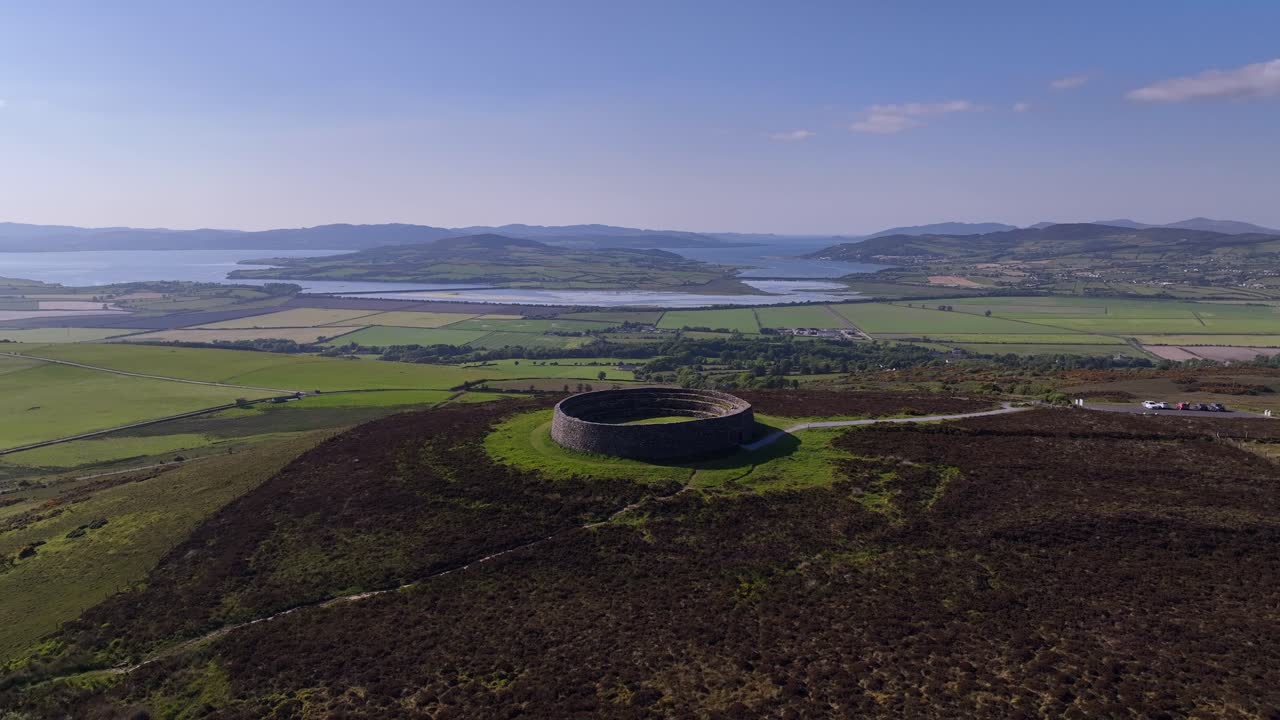 Grianan of Aileach, County Donegal, Ireland, June 2023. Drone pulls backward ascending to reveal the iconic Gaelic Ringfort and view north with Inch Wildfowl Reserve and Lough Swilly in the distance.