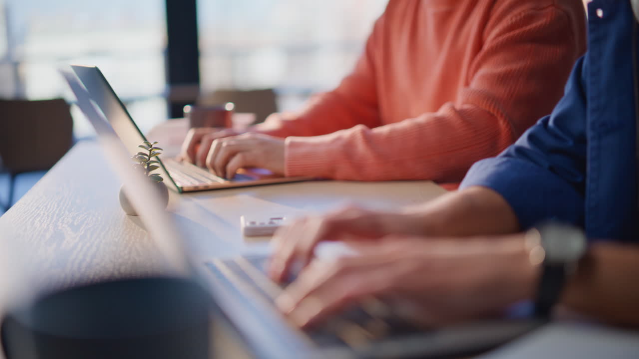 IT workers hands typing laptops at modern workspace closeup. Employees working