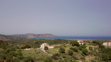 aerial flyover of luxury greek villa patio - loungers revealing coastline in the distance in crete, greece