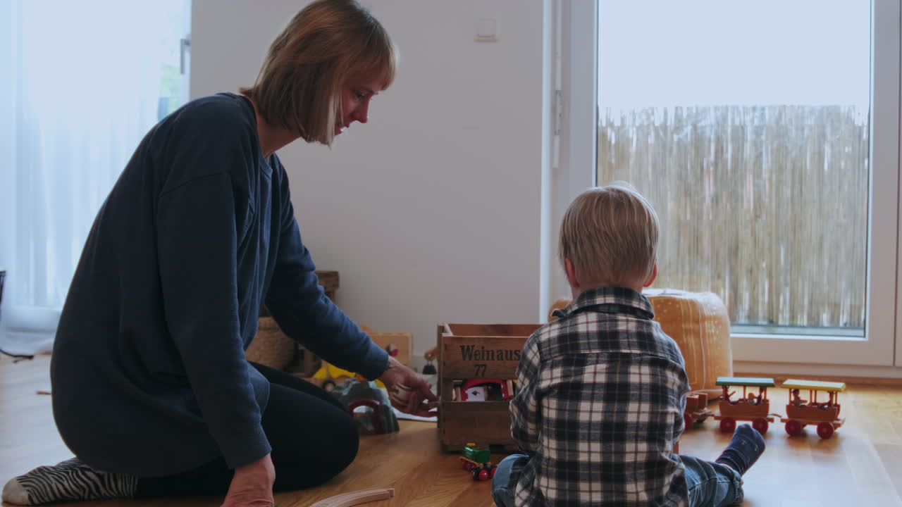 madre e hijo sentados en el suelo y construyendo un tren de juguete juntos