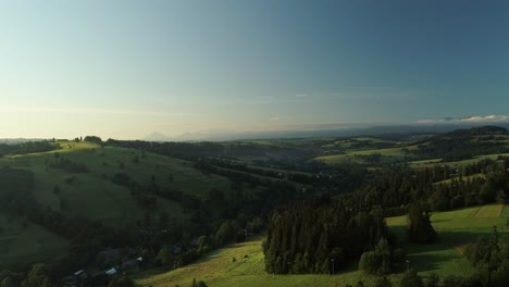 beautiful landscape with meadows rolling through forested hills in springtime - aerial drone shot