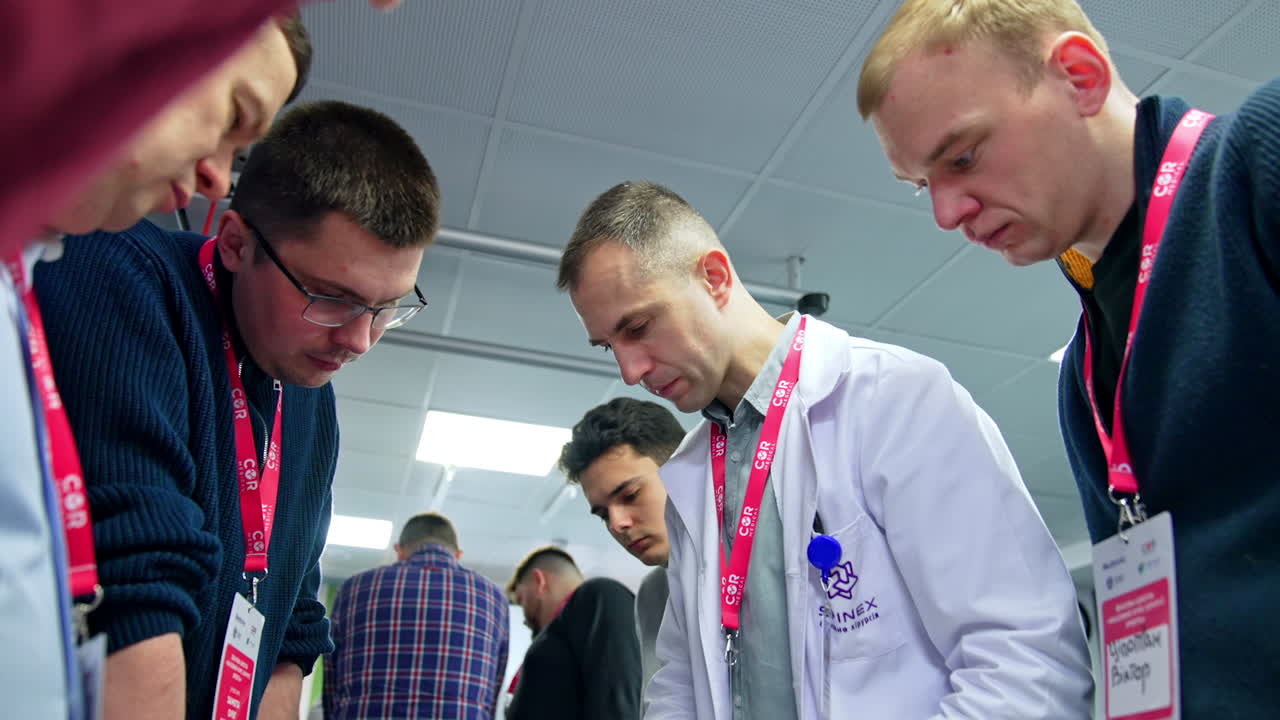 Lecturer and a group of students leaned over the table with studying materials. Neurosurgery practice.
