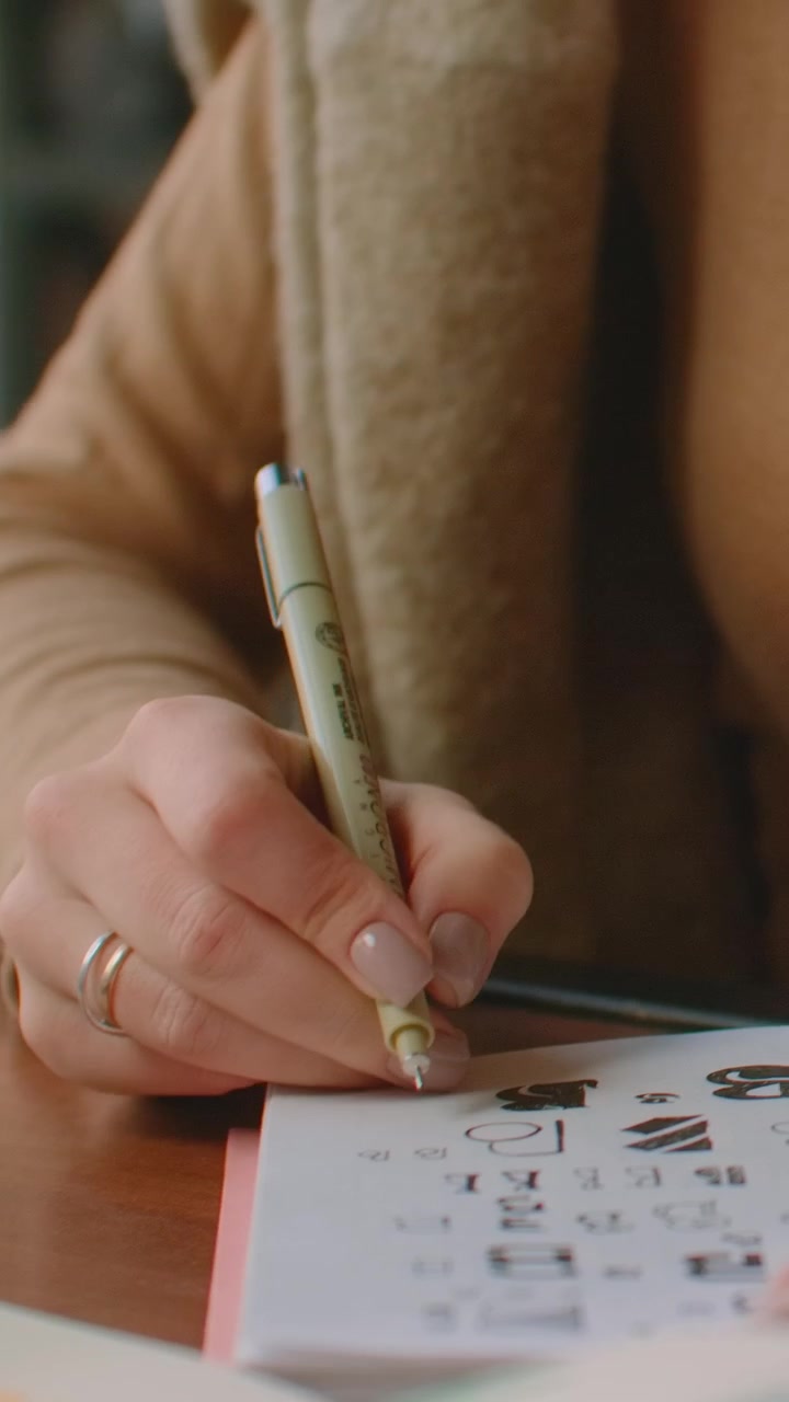 Young Woman Drawing Letters in a Sketchbook