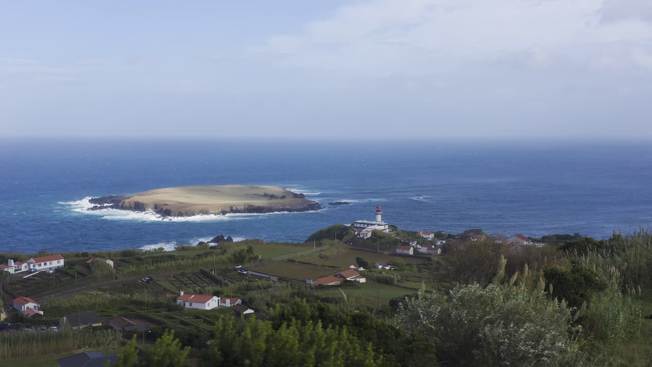 вид с дрона на сельскую прибрежную деревню с маяком и остров в атлантическом океане, облачное небо в топографии, остров сан-жоржи, азорские острова, португалия
