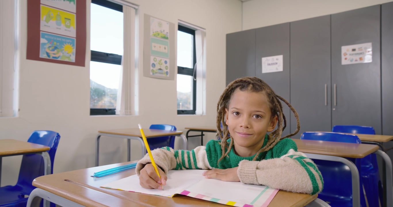 Telecamera che segue un bambino africano in classe che scrive su un quaderno con la matita, mentre fa i compiti, con spazio per il testo