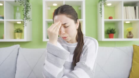 asian young woman with migraine rubbing her head.