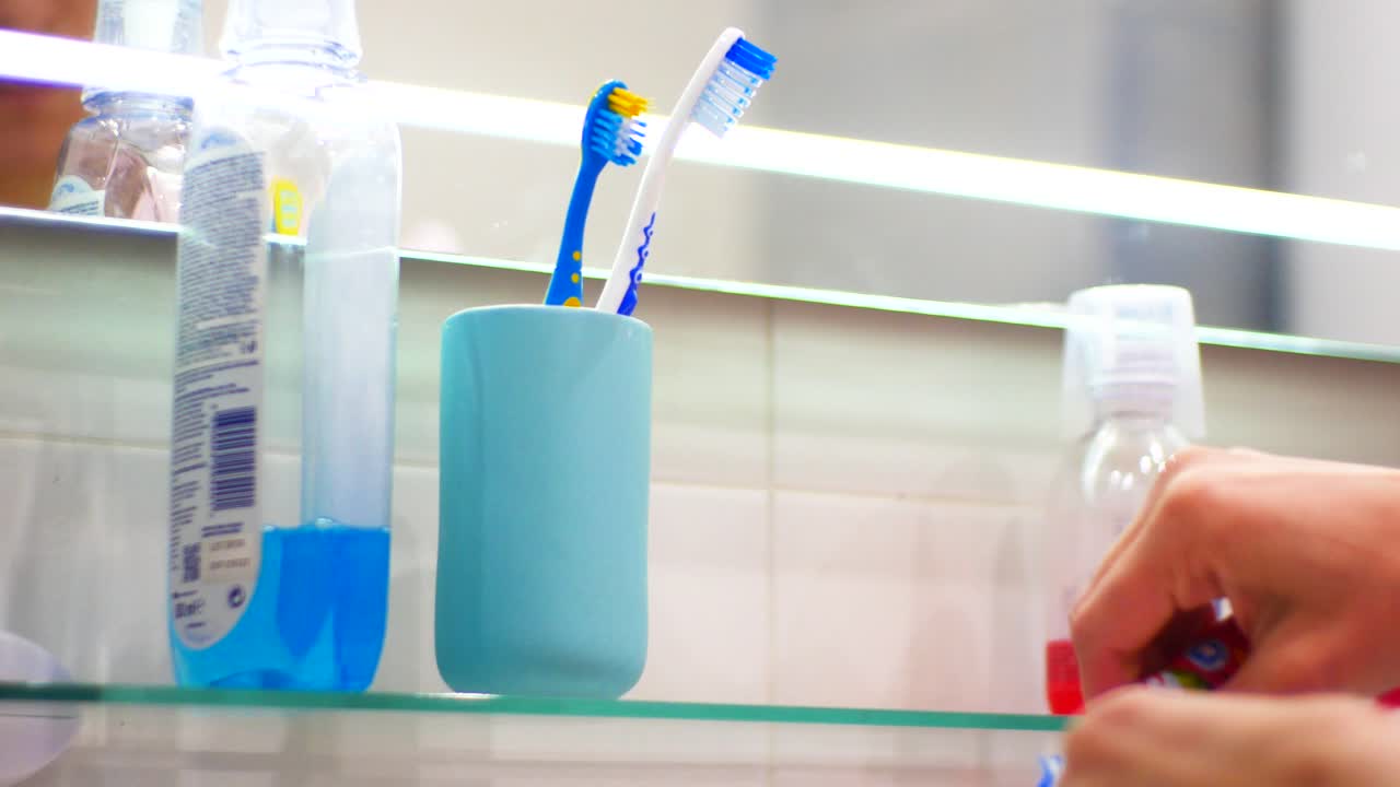 화장실에 있는 여자들은 칫솔에 치약을 바르고 이를 닦는다