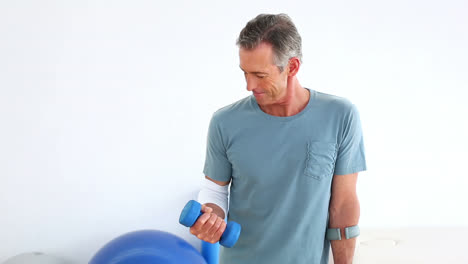 Injured-mature-patient-on-crutches-lifting-dumbbell