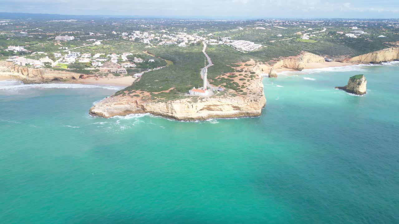 Aerial shot of Ferragudo, Algarve, showcasing cliffs, lighthouse, and turquoise sea