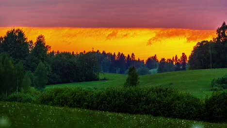 Beautiful-orange-sunset-sky-over-green-rolling-hills-and-fields