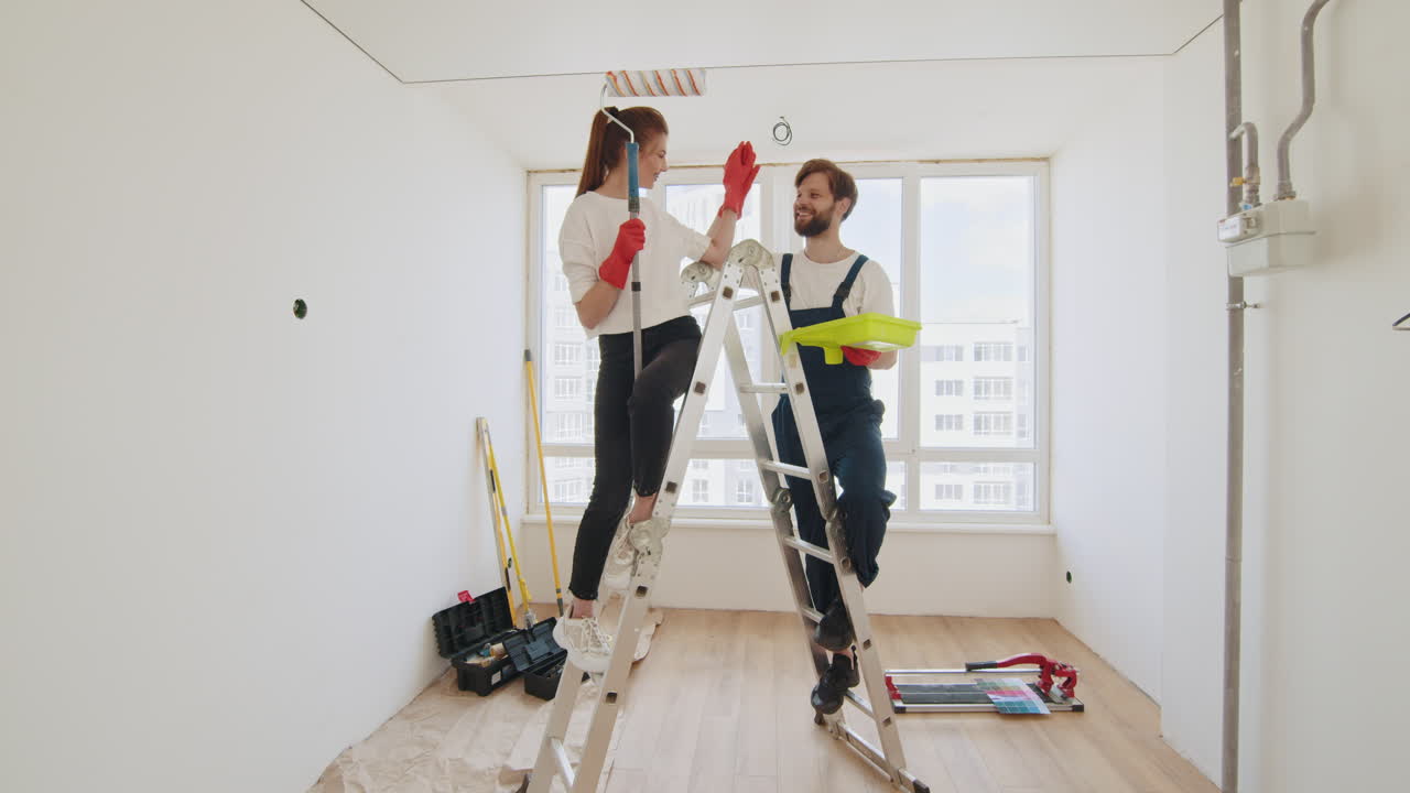 una pareja pintando una habitación.