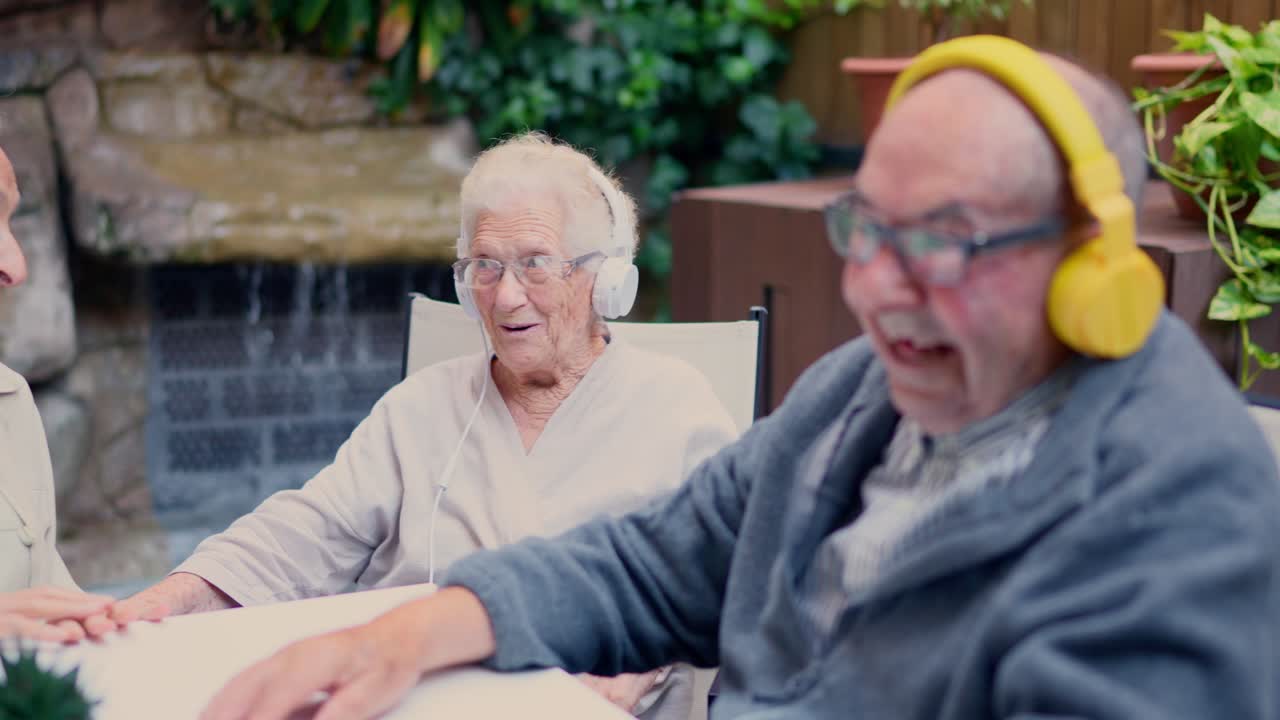 Elderly couple enjoying music together with headphones in their garden