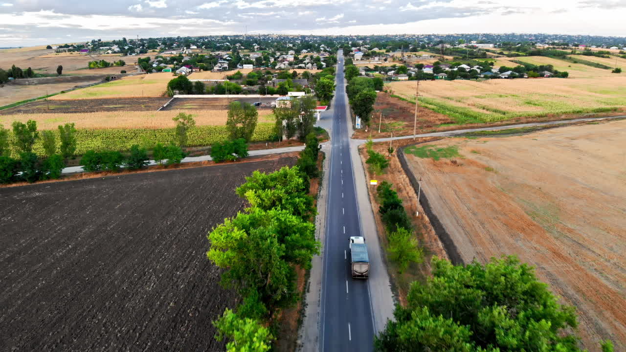 Aerial drone view of a road with moving car in highland. Green fields and hills from north part of Moldova