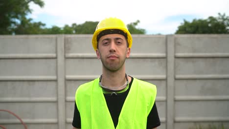 construction worker in yellow hard hat and reflective vest pointing finger to head