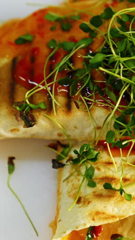 delicious dish in the restaurant. yummy pita poured with sauce on table.tasty meal decorated with green sprouts. ready to eat. close-up. vertical video