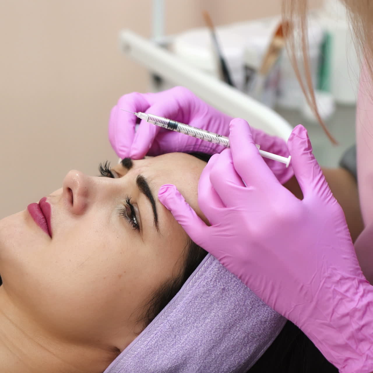 Young beautiful dark-haired woman gets rejuvenating facial injections. Work of the cosmetologist. Aesthetic cosmetology.